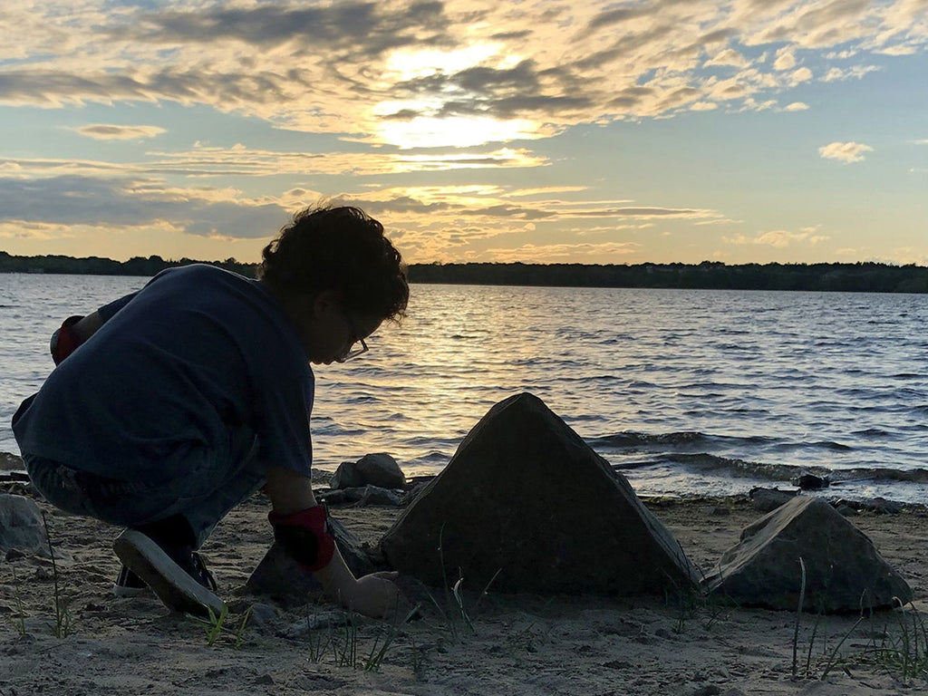 a boy building pyramids out of some rocks on the beach
