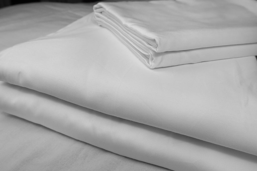 folded pearl white sheet set on white backdrop