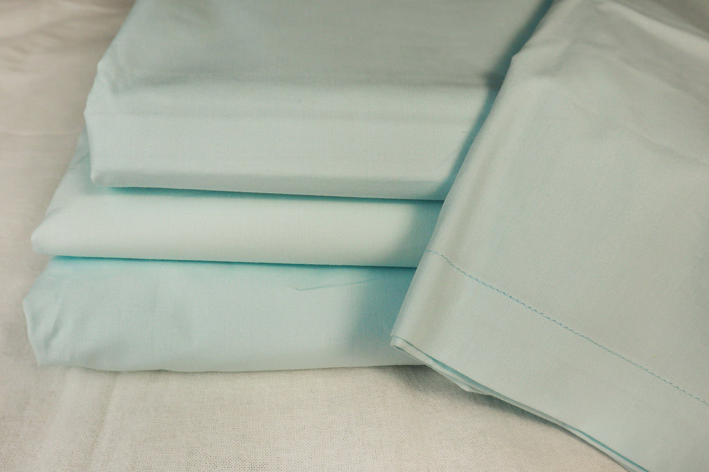 folded powder blue sheet set on a bed