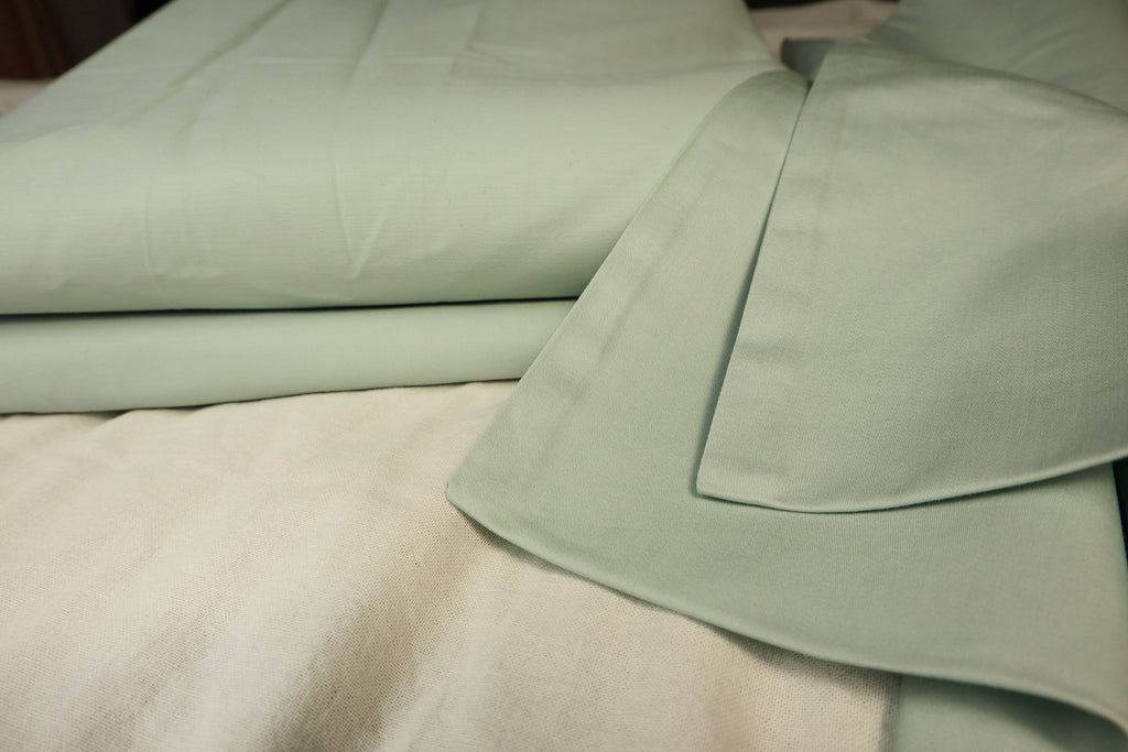 folded Sea Salt sheet set on a bed