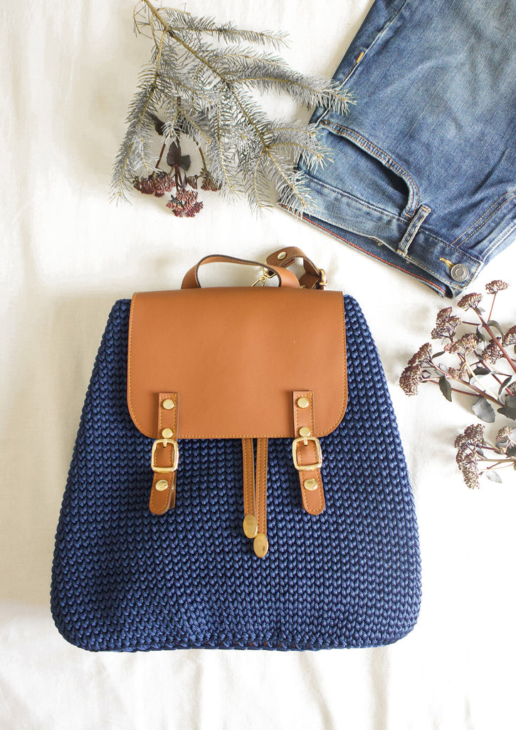 Handmade Crochet Backpack - Deep Blue on white bed with blue jeans