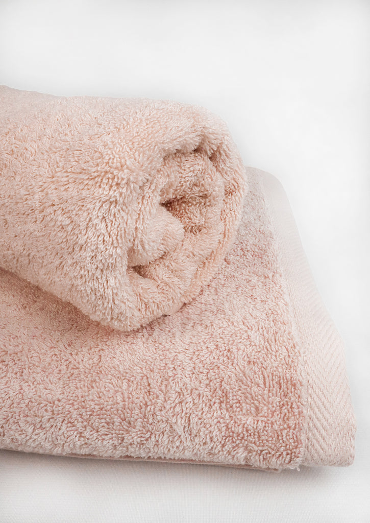 one rolled towel over other folded one - cloud pink towel