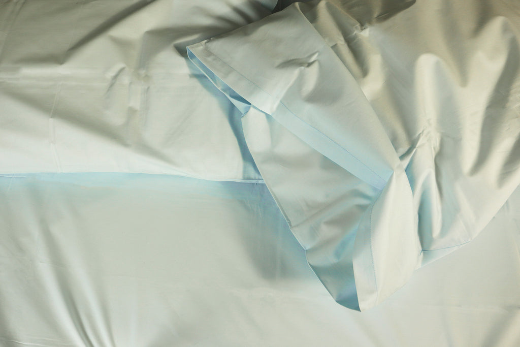 two messy pillows on a bed - powder blue sheet set