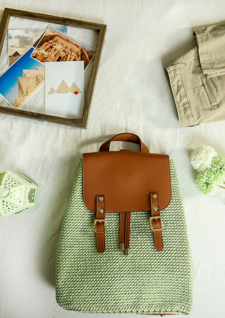 Handmade Crochet Backpack - Pistachio - flay lay on white bed with beige pants